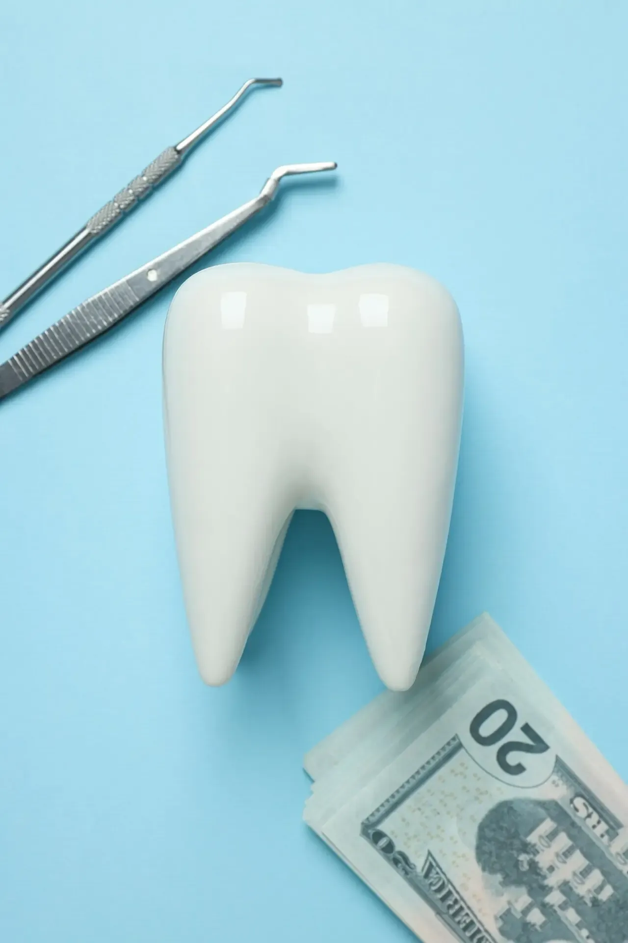 Dental tools, a decorative tooth and money on a blue background