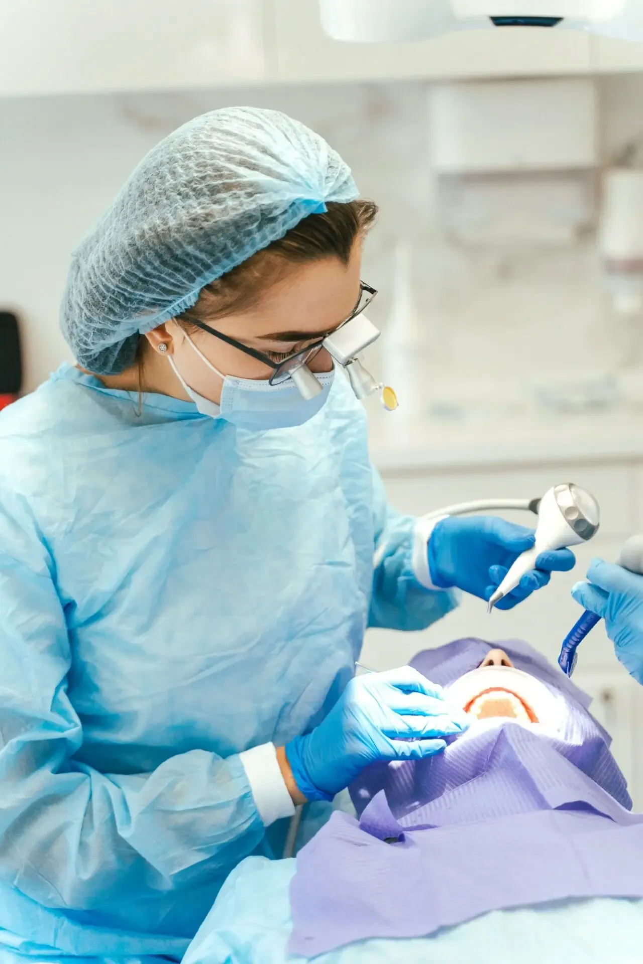 A dental surgeon wearing a head-mounted microscope during a procedure