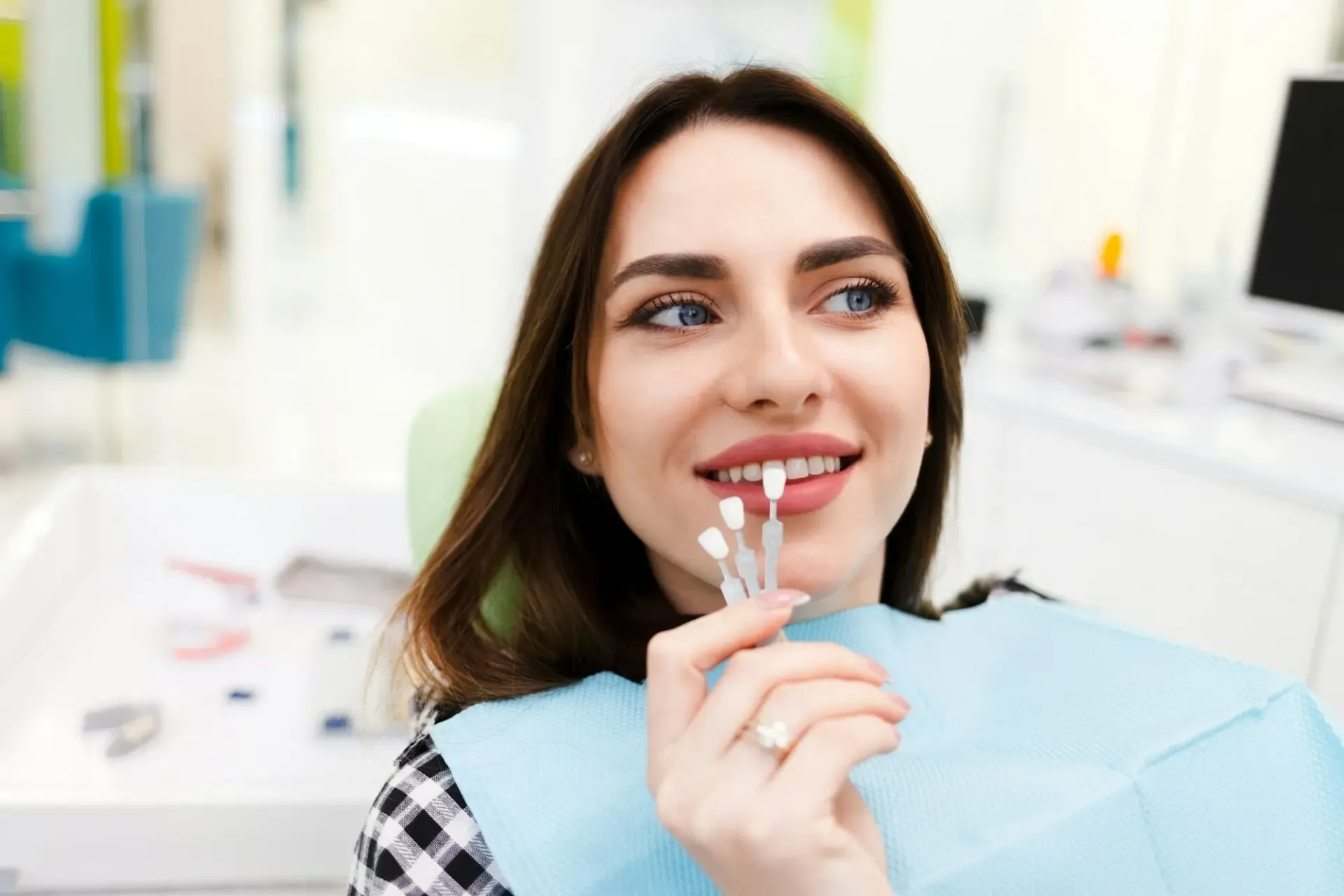 A patient choosing the color of veneers at the dentist's office