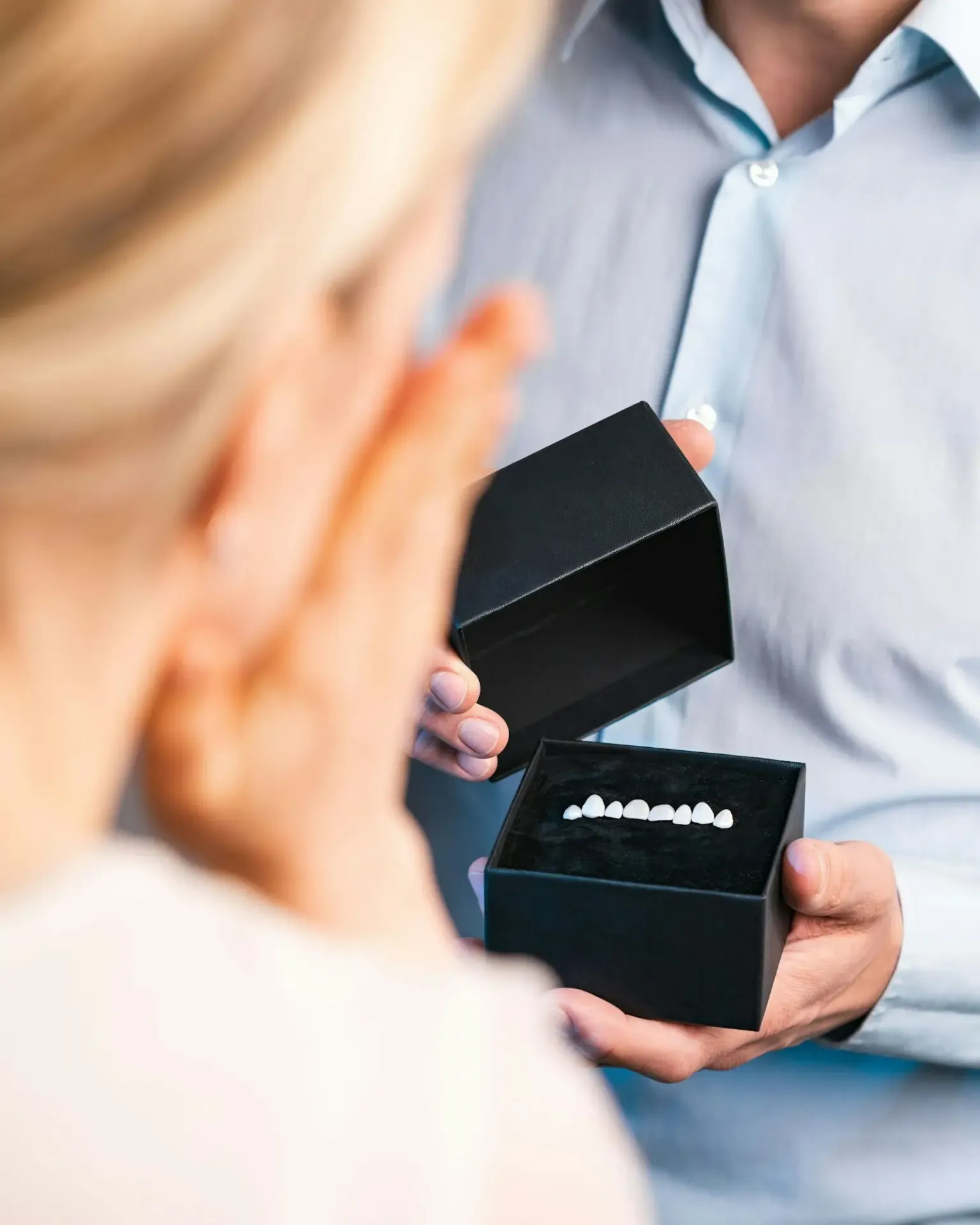 A man surprising a woman with dental veneers in a black box
