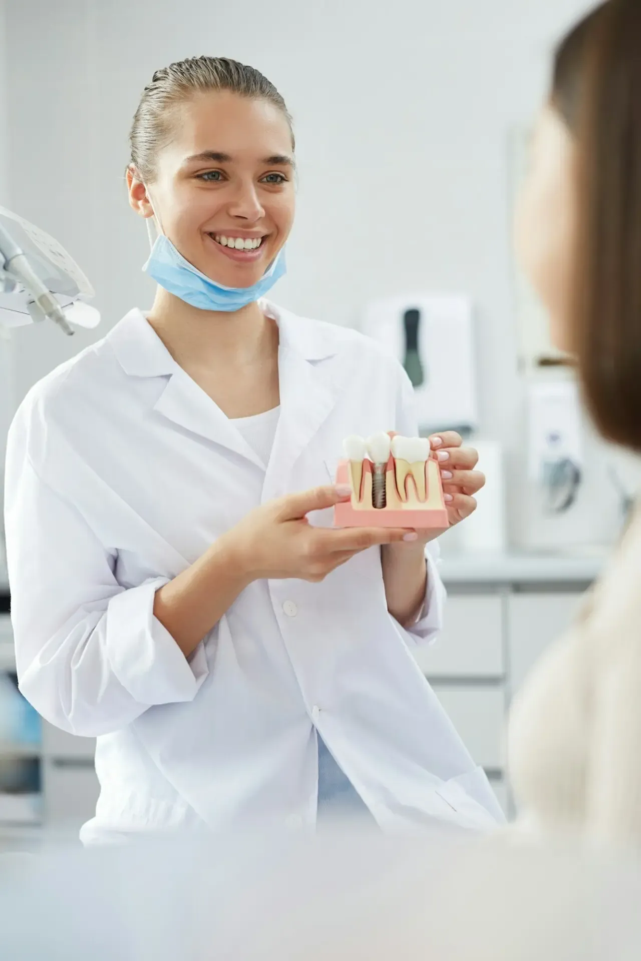A smiling dentist holding a tooth model